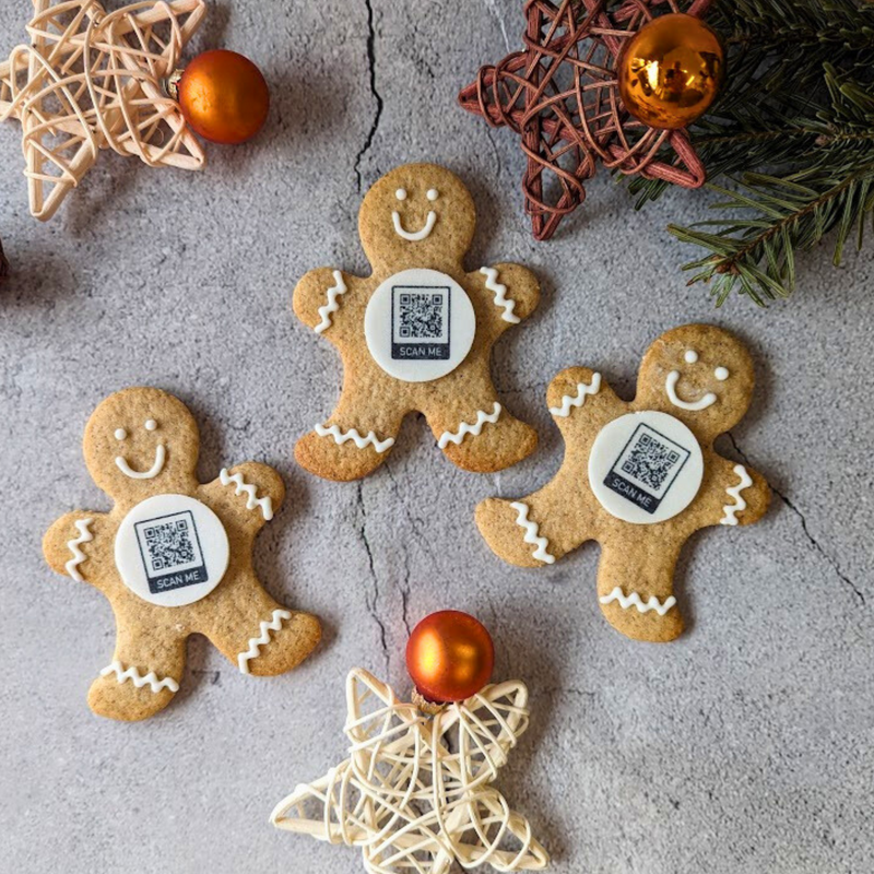 Branded gingerbread man biscuit with branded logo potential, on slate with festive greenery.