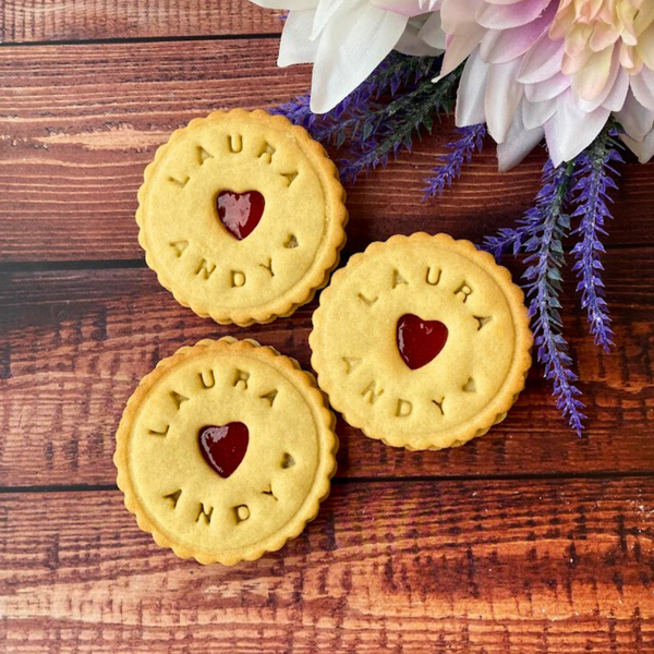 Close-up of Custom Wedding Names cookies with heart-shaped holes, stacked on a stone table 