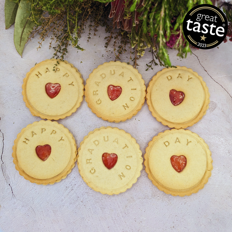 heart-shaped biscuits with red jam filling, arranged on a grey table