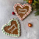 Two heart-shaped iced Christmas cookies with the message "Merry Xmas" and festive decorations. 