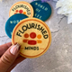 Four round butter biscuits printed with colourful "Flourished Minds" logo