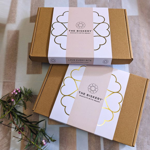 Boxes labelled 'The Biskery' and 'Love Every Bite' sit on a table, filled with dogs biscuits.