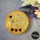 Giant Cookie | happy anniversary in a gift box, decorated with white icing and the name "Happy anniversary". Festive decorations and a Great Taste award logo are visible in the background.